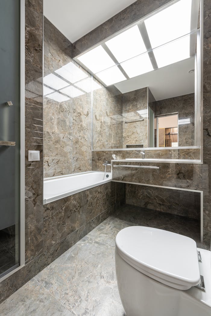 Sleek marble-tiled bathroom with modern fixtures and ample lighting.